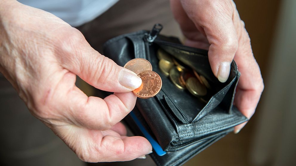 En man som tar fram mynt ur sin plånbok.