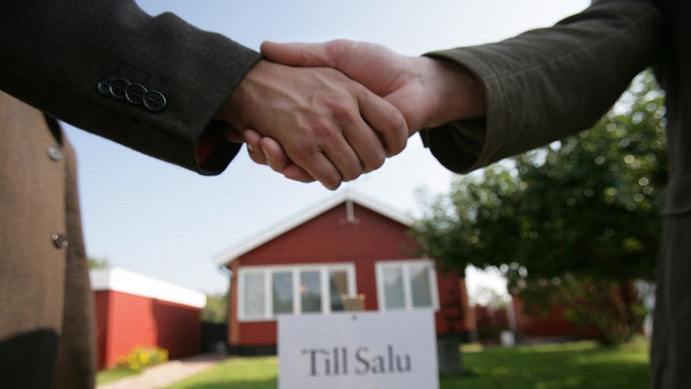 Två personer som skakar hand framför ett hus som sålts.