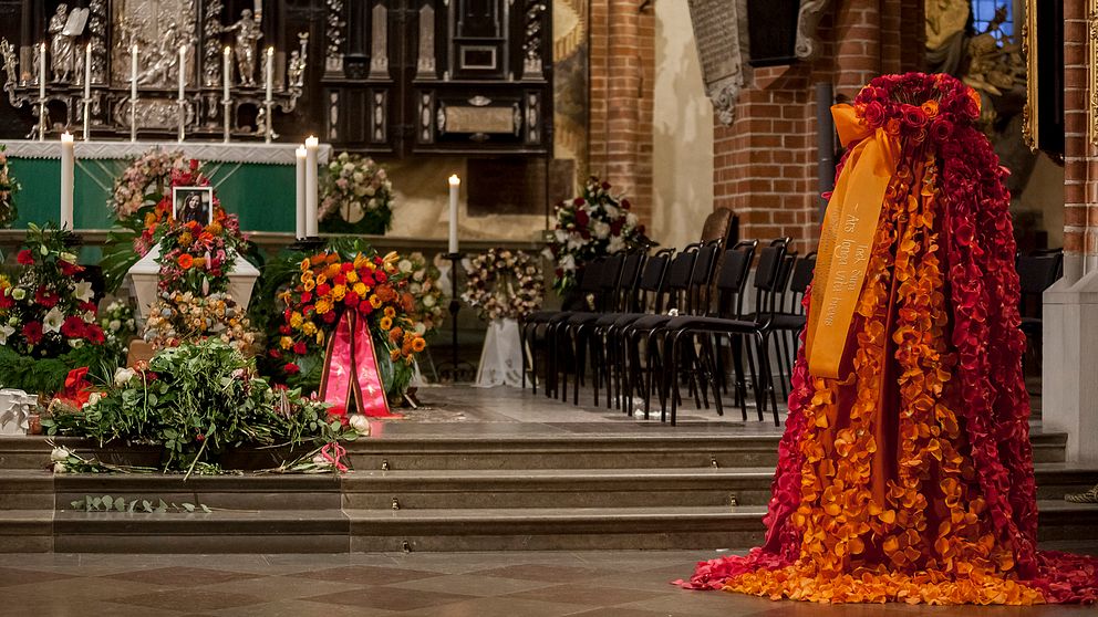 Bilden föreställer Sara Danius kista och en klänning gjord av blommor likt den hon bar på Nobelfesten förra året.