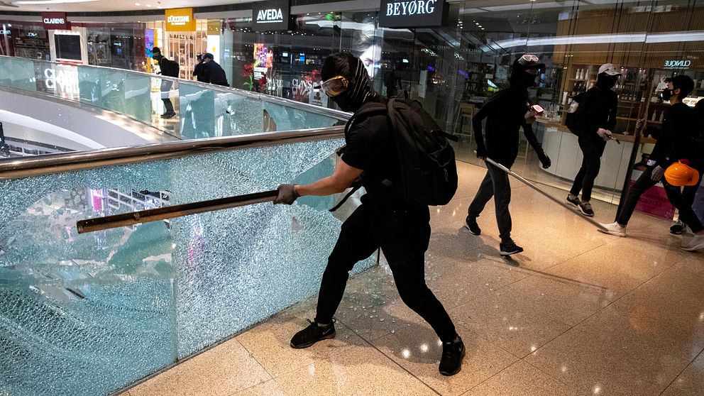 Bilden föreställer demonstrant som slår sönder ett glasräcke i en galleri.
