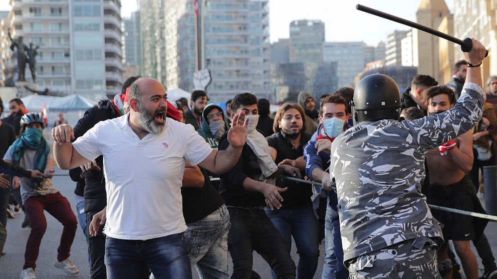 Polisen i Libanon tar till med batong när de försöker skingra den demonstrerande folkmassan.