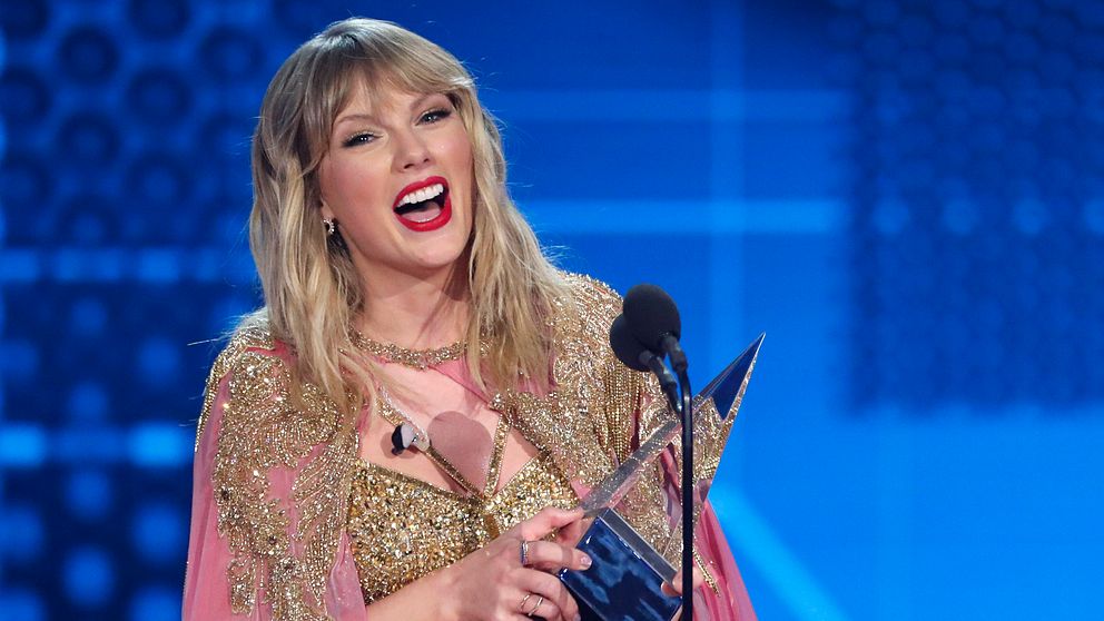 Taylor Swift ler stort under ett tal där hon håller sin statyett.