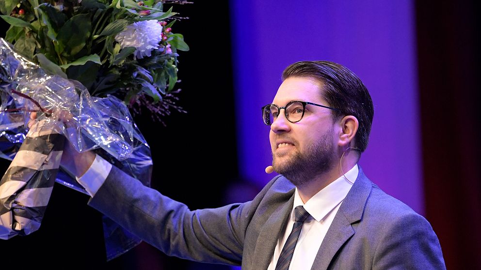 Jimmie Åkesson, Sverigedemokraternas partiledare håller i en blomma.