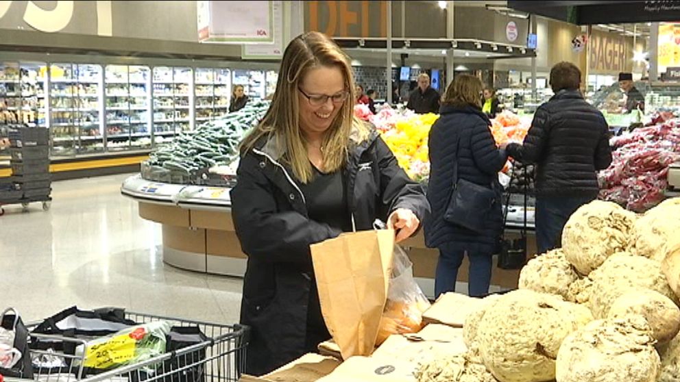 Camilla Gartz står i en butik och plockar i frukt i en matavfallspåse