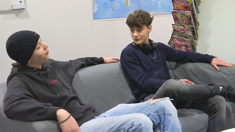 Två 15-åringar sitter i en soffa på sin skola.
