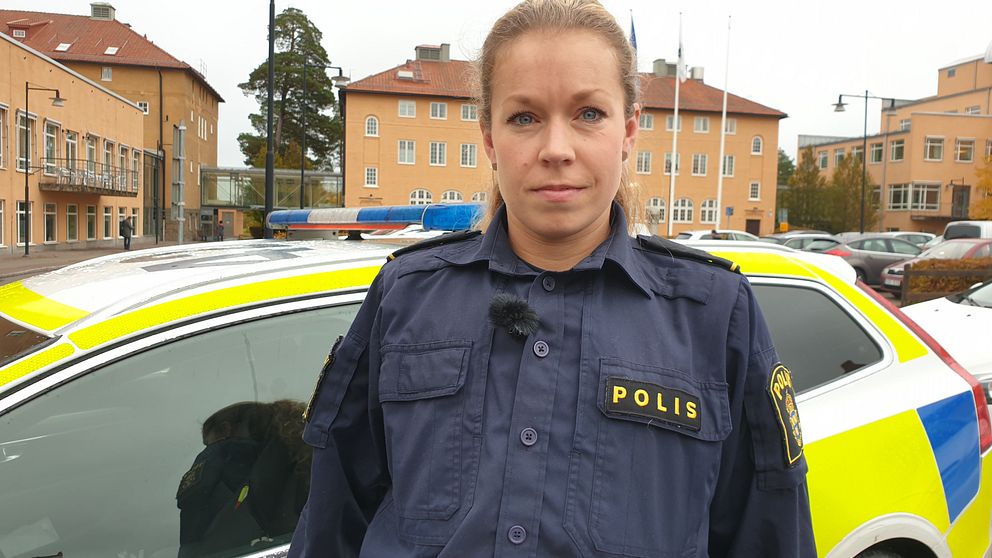 Porträttbild på Angelica som har polisuniform och står framför sin polisbil