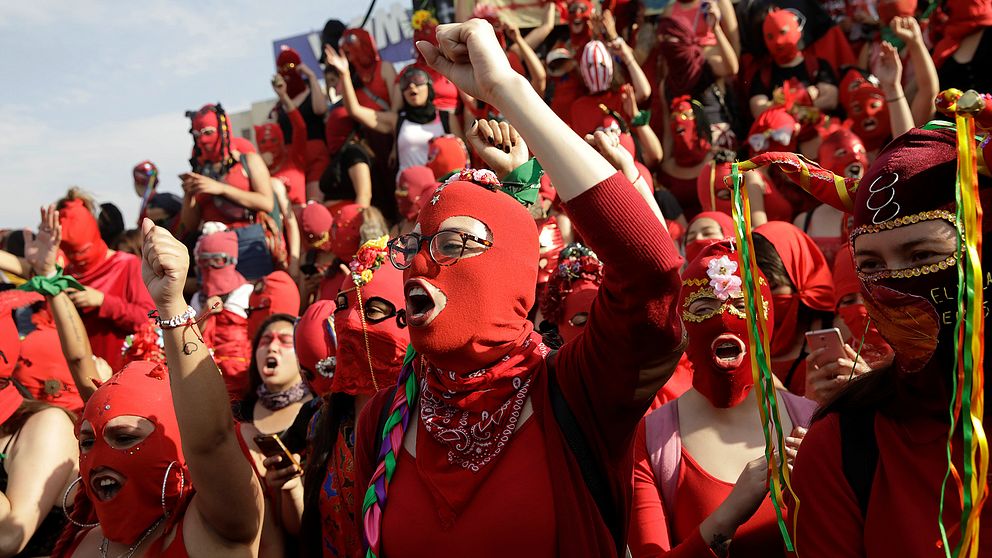 Kvinnor i röda masker protesterar mot kvinnovåld och regeringen i Chile.