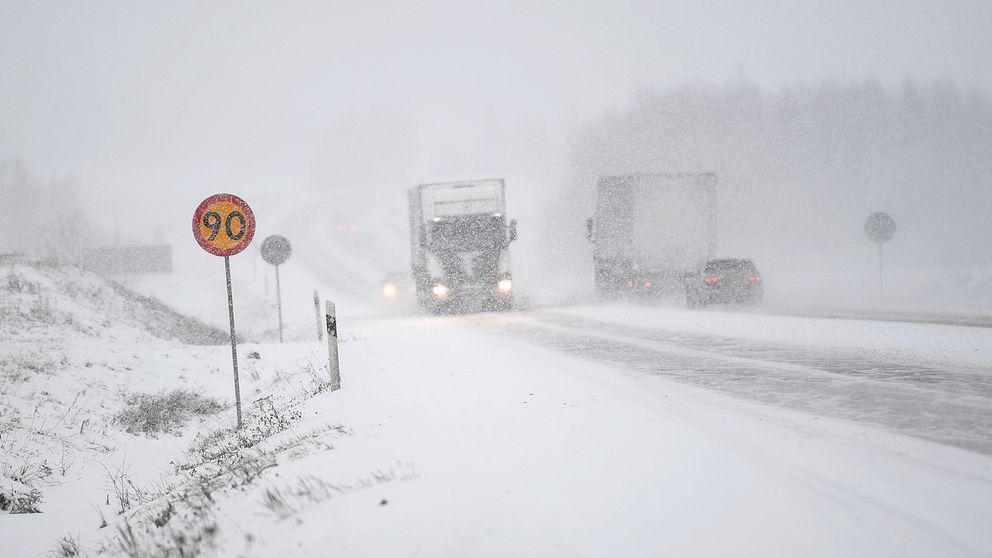Mycket snö på väg med lastbilar och bilar i snöröken.