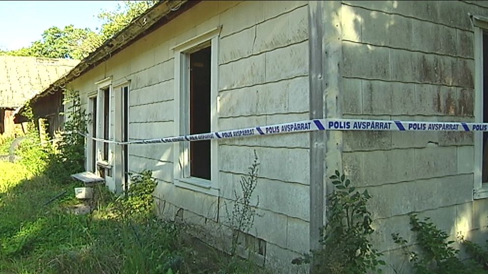 Ett lågt hus på en vildvuxen gräsmatta, ett plastband med texten polis avspärrat sitter runt fasaden.