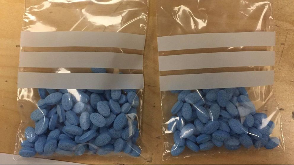 Två genomskinliga plastpåsar med blå tabletter i.