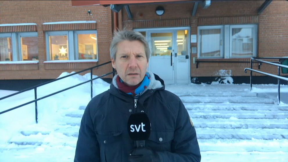 reportern, en medelålders man, står med mikrofon utanför den snöiga trappen till tingsrätten