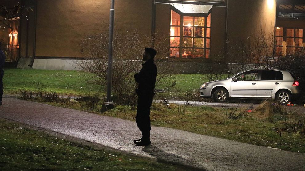 Polis står på brottsplats, bil och hus syns också i bild.