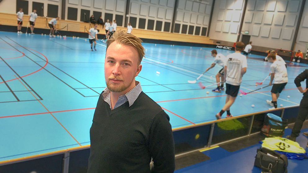 Porträttfoto på Jakob Westerlund, distriktschef på Gästriklands och Hälsinglands innebandyförbund. I bakgrunden spelar ungdomar innebandy.