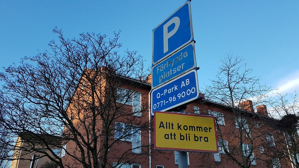 Parkeringsskyltar och en gulröd upplysningsskylt med texten ”Allt kommer att bli bra”.