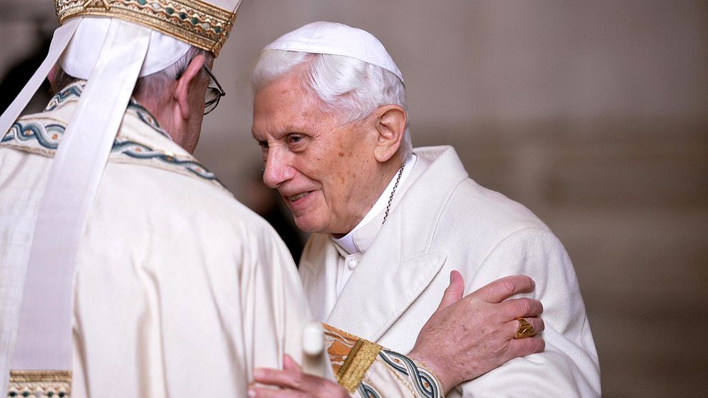 Till vänster ryggen av påven Franciskus som talar med påven emeritus Benedictus XVI. Arkivbild.