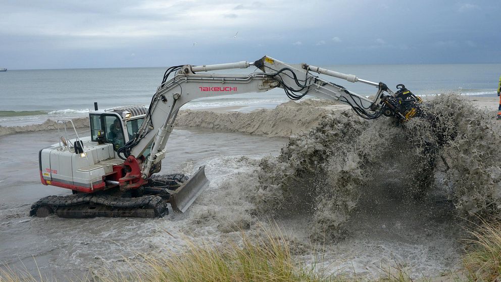 grävmaskin lastar sand på stranden i Löderup