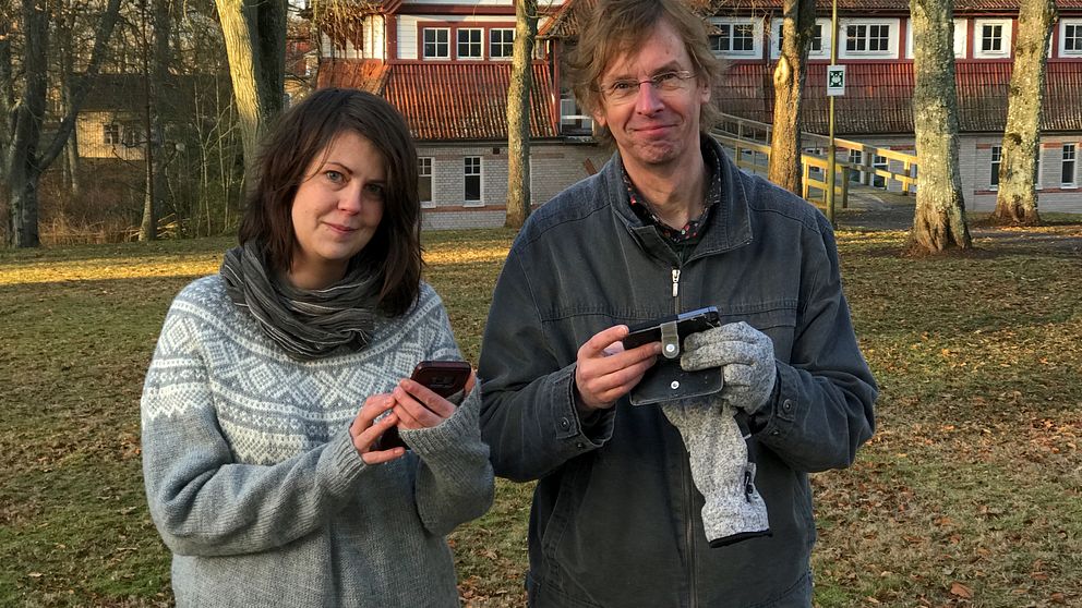 Therese Pohl och Mikael Lundgren med mobiltelefoner i kurortsparken i Lundsbrunn
