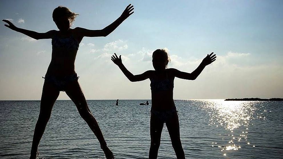 Barn hoppar ur havet.