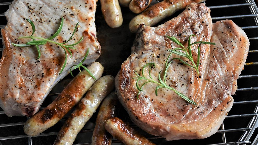 Grillade fläskkotletter som ligger på en grill med några korvar.