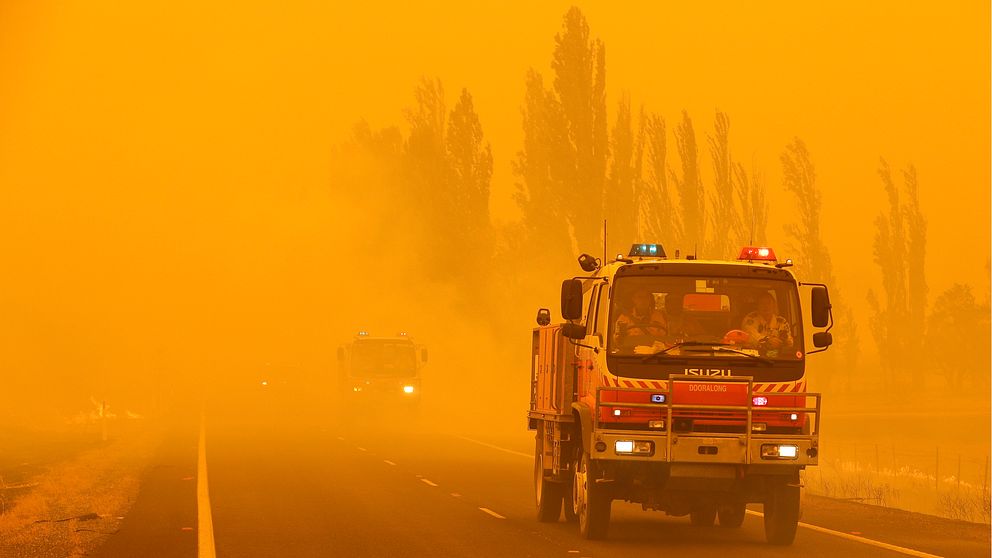 En brandbil kör genom rödgul rök i Australien
