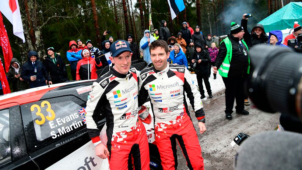 Elfyn Evans och Scott Martin poserar för bilder samtidigt som publik syns i bakgrunden.