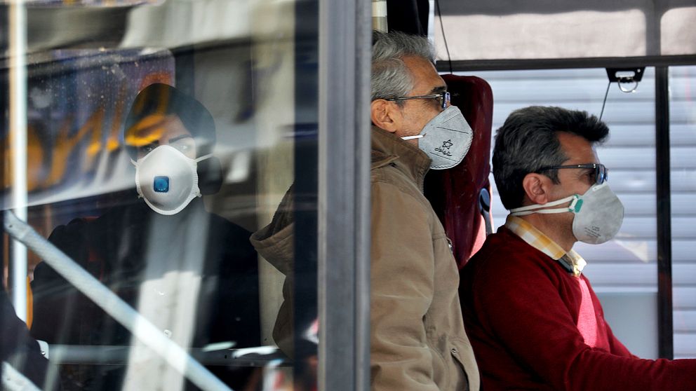 Människor med ansiktsmask åker buss i Teheran.