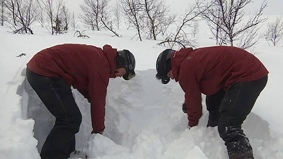Två personer står och gräver i en snödriva