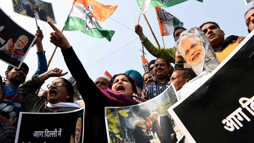 Indiska demonstranter håller upp flaggor och skyltar.