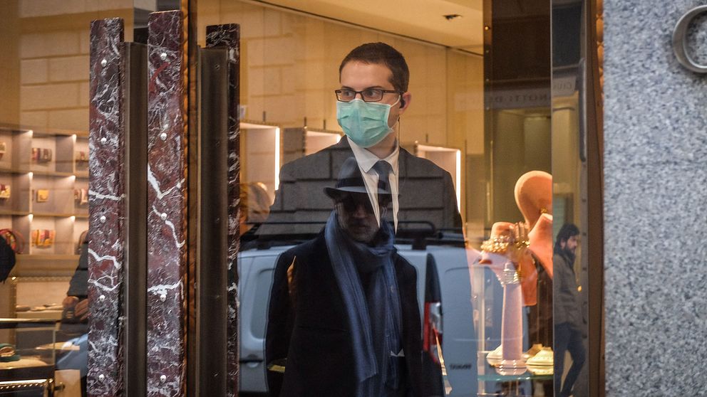 En anställd i modebutik i Milano i Italien som bär munskydd på grund av coronavirus.