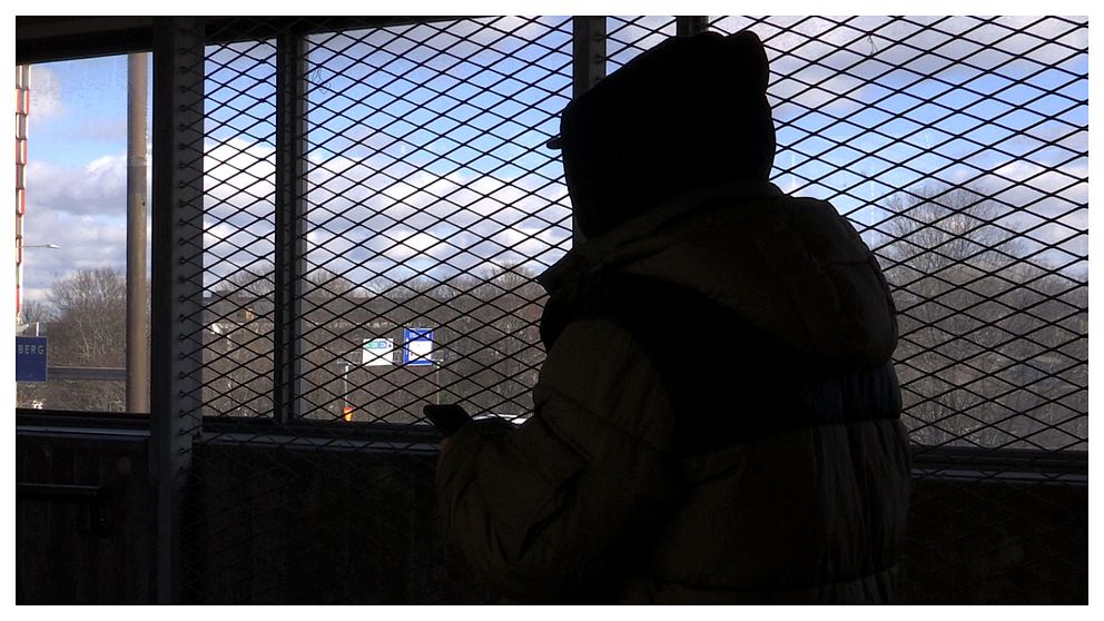 Mörk silhuett av en ung man som står vid ett fönster. Mannen är anonym och bilden är icensatt för att visa en bild av de många anonyma ungdomsrånarna i Stockholm.