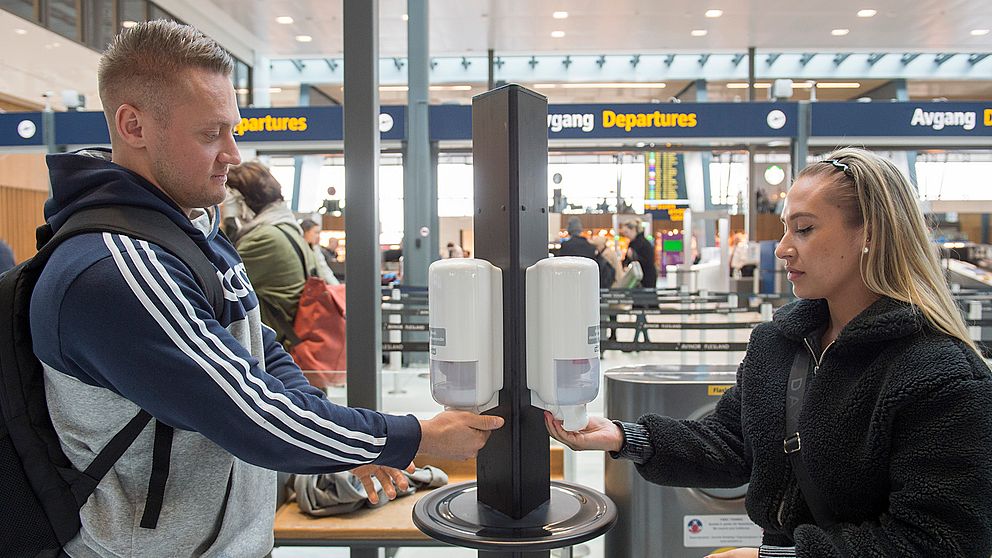 Två resenärer tvättar händerna på flygplatsen i Bergen.
