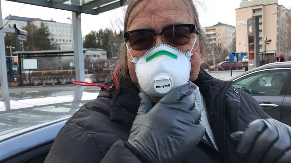 Man som är högriskpatient med munskydd och svarta handskar utanför sjukhuset i Umeå