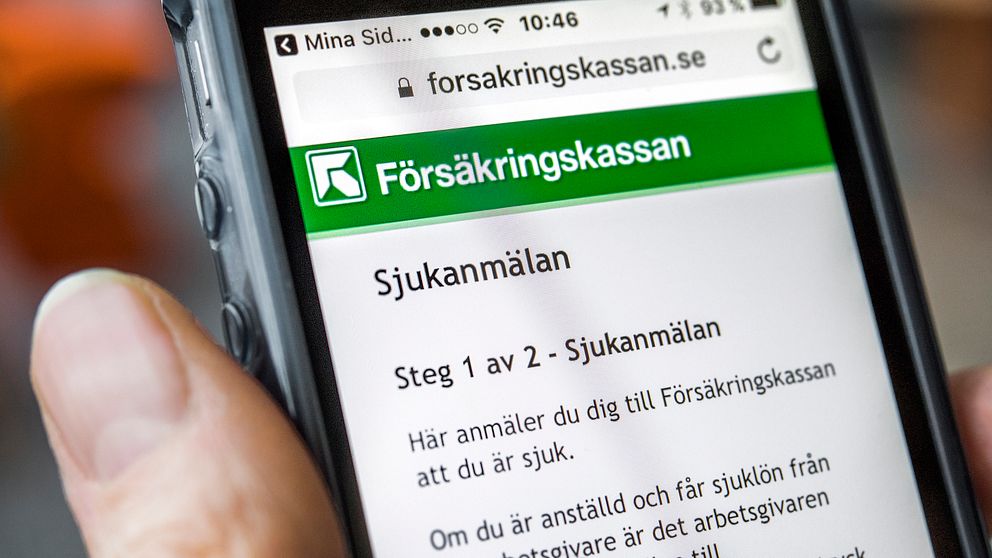 En närbild av en hand som håller i en mobiltelefon. På skärmen syns försäkringskassans hemsida.