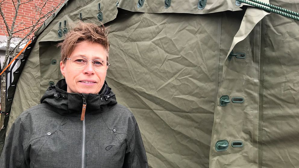 Kvinna står framför ett grönt corona-tält.
