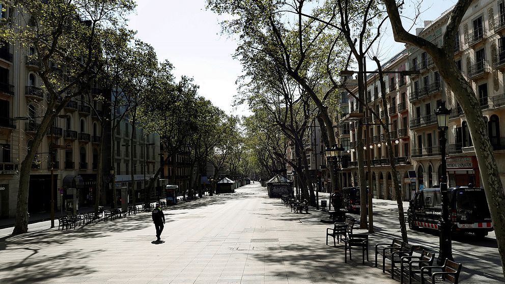 En ensam person syns promenera ned för en folktom gata i Barcelona.