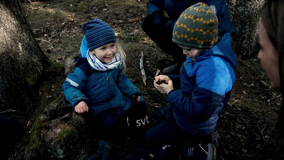 Två barn som leker i skogen.