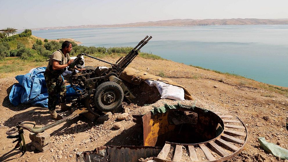 Kurdisk peshmerga-stridande gör sitt vapen redo för strid vid Mosuldammen i Irak.