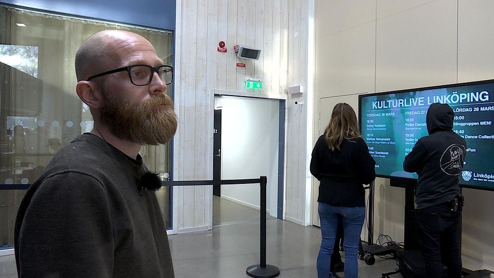 Konstnären står framför en tv-skärm med programmet för Kulturlive Linköping