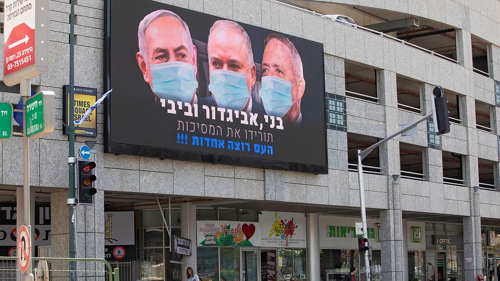 Bild på Israels premiärminister Benjamin Netanyahu, tidigare försvarsministern Yisrael Beiteinu samt oppositionsledaren Benny Gantz i förda munskydd på en reklambild i den israeliska staden Ramat Gan.