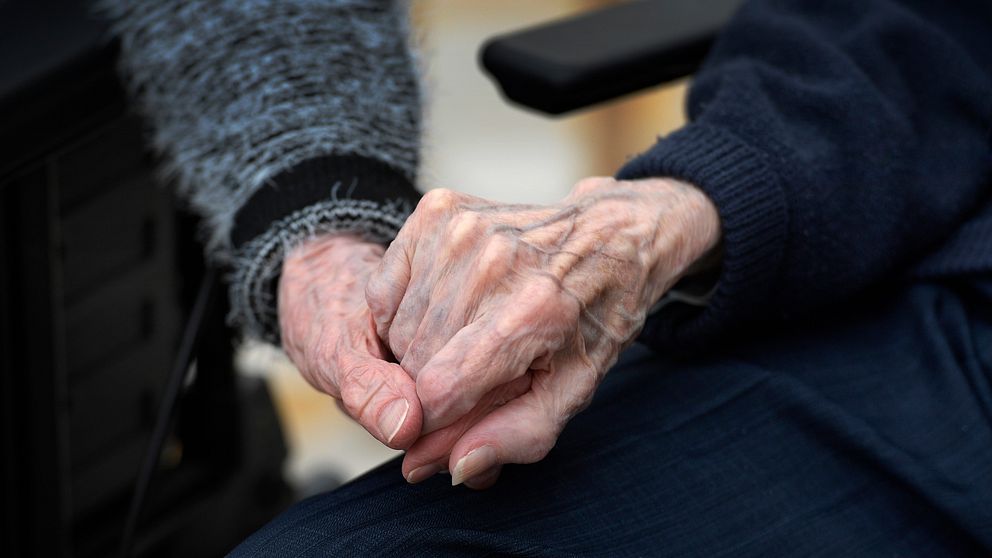 Äldre personer håller varandra i handen.