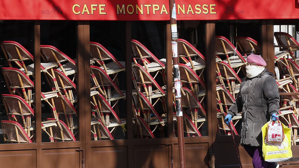 En kvinna går förbi en tillfälligt stängd restaurang i Paris.