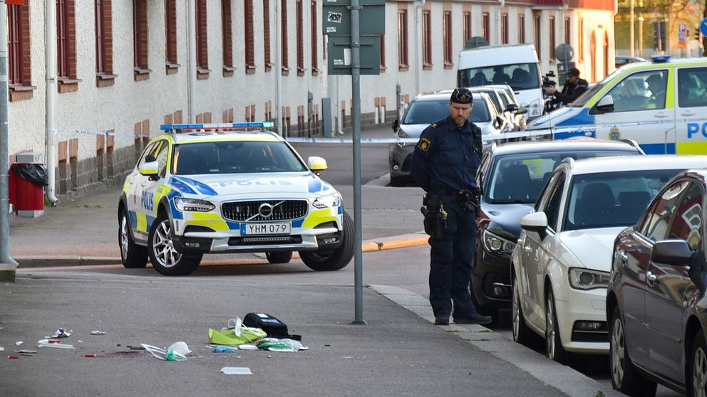 polisbilar och bilar vid trottoar, polisman står och tittar på saker som ligger på marken