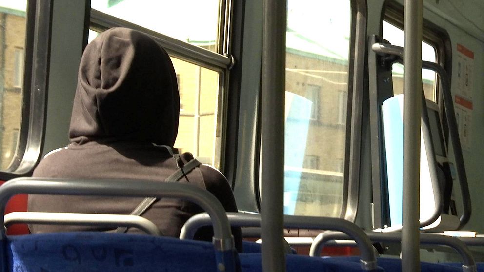 Kvinna på buss med luva.