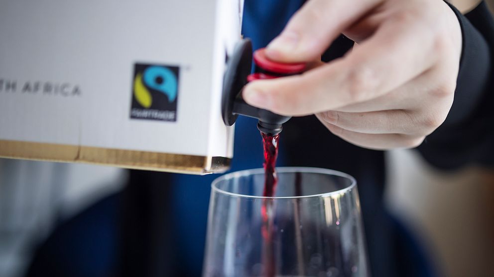 En hand som trycker fram vin ur en box.