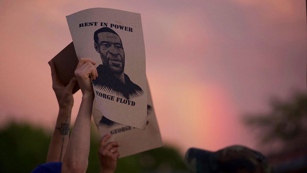 En demonstrant i Minneapolis håller upp en skylt med bild på George Floyd.