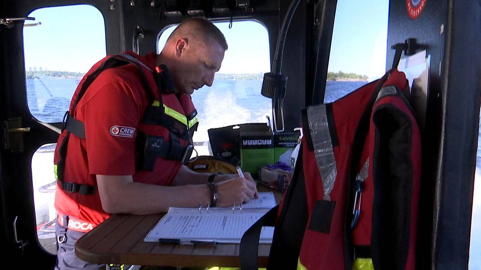 Stationsansvarig på Sjöräddningen i Stockholm Mikael Carlsson, för protokoll i hytten på sin båt. Utanför fönstret syns ett böljande blått hav.