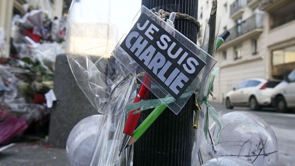 Blommor och pennor upphängda utanför Charlie Hebdos redaktion efter attentatet.