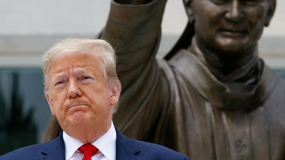 Donald Trump när han poserade framför statyn över påven Johannes Paulus II i tisdags.