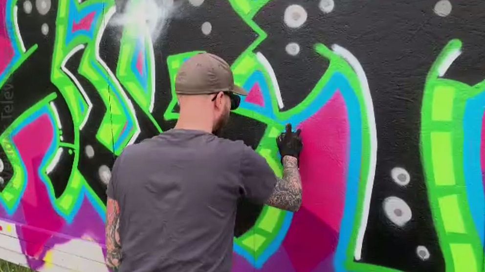 Graffitimålaren Johan Hjort målar graffiti på en vägg vid skateboardrampen i Kap-området.