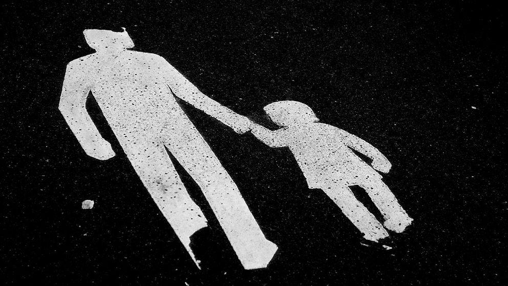 en svartvit teckning på en vuxen som håller ett barn i handen